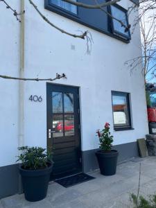 a white building with a black door and two potted plants at Appartement Juf in Lisse