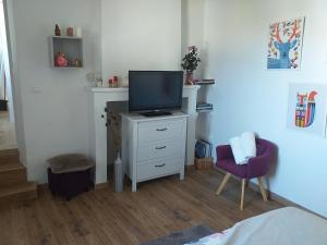 sypialnia z telewizorem na białej komodzie w obiekcie Deux M w mieście Villes-sur-Auzon