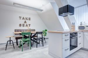 uma cozinha com armários brancos e uma mesa com cadeiras verdes em Pressehaus Apartment Obermarkt Spa em Mühlhausen