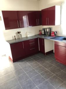 uma cozinha com armários vermelhos e piso em azulejo em Maison neuve 8 couchages em Ginestet