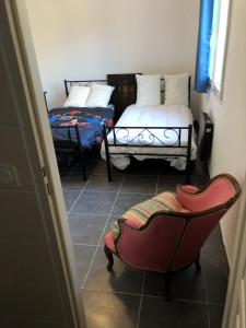 um pequeno quarto com 2 camas e uma cadeira em Maison neuve 8 couchages em Ginestet