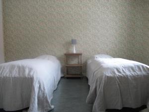 two beds in a room with white sheets at Conciërgewoning van het gerechtsgebouw. in Ragunda