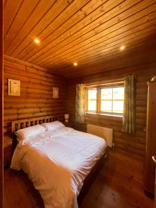 a bedroom with a bed in a wooden cabin at Beautiful 2 Bedroom Log Cabin With Private Hot Tub - Elm in Leominster
