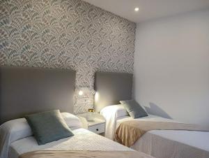 1 dormitorio con 2 camas y pared con papel pintado en PortoSantiago Boutique & Rooms, en Portomarín