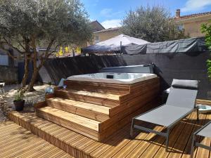 bañera de hidromasaje en una terraza de madera con silla en Deux M, en Villes-sur-Auzon