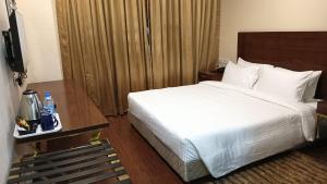a hotel room with a bed and a television at Layalee Grande Hotel Chennai in Chennai