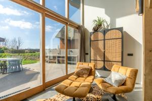 a living room with two chairs and a large window at Buytenplaats Villa 181 in De Koog