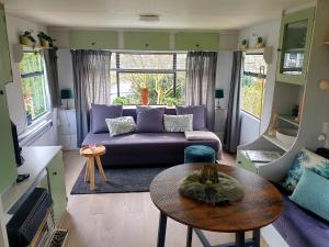 een woonkamer met een paarse bank en een tafel bij Vintage stacaravan Fereale Grou in Grou