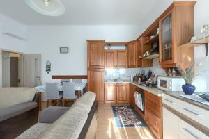 a kitchen with wooden cabinets and a living room at Aida Pula apartment in Pula