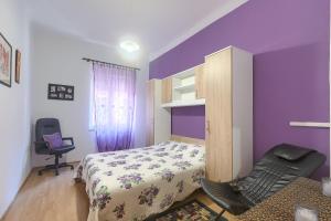 a bedroom with purple walls and a bed and a chair at Aida Pula apartment in Pula