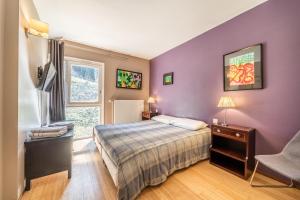 una camera da letto con pareti viola, un letto e una sedia di Gîte Le Jorat - Appartement A a Bogève