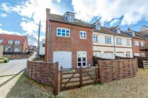 a brick house with a fence in front of it at Bakers Yard in Wells next the Sea