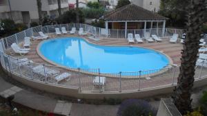 a large swimming pool with lounge chairs at Appartement clim piscine garage in Le Grau-du-Roi