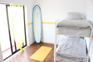 um quarto com um beliche e uma prancha de surf na parede em Rich & Poor Hostel Albufeira em Albufeira