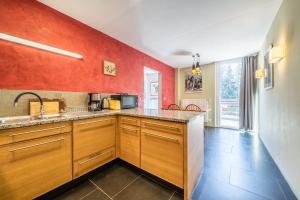 una cocina con armarios de madera y una pared roja en Gîte Le Jorat - Appartement B, en Bogève