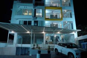 a white car parked in front of a building at night at The White Orchid Luxury Service Apartments in Ernakulam