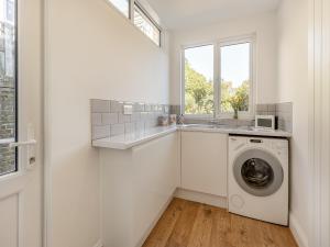 een witte wasruimte met een wastafel en een wasmachine bij St Mildreds Villa in Ramsgate