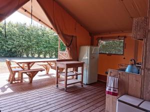 a kitchen with a table and a refrigerator on a deck at Tente Lodge 13 couchages in Vaas