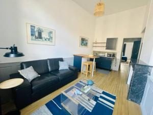 ein Wohnzimmer mit einem schwarzen Sofa und einem Tisch in der Unterkunft Appartement Petit Messier in Senones
