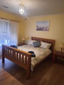 1 Schlafzimmer mit einem Bett, 2 Tischen und einem Kronleuchter in der Unterkunft Cottage by the Sea in Port Adelaide