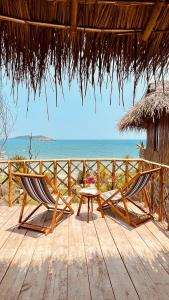 two chairs and a table on a deck with the ocean at Life's A Beach in Quy Nhon