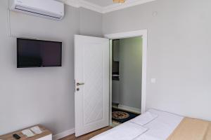 a white bedroom with a bed and a tv at QZEN SUİT APART OTEL in Trabzon