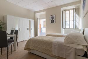 a bedroom with two beds and a table and a desk at Center Rooms in Piacenza