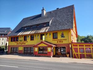 um edifício amarelo e vermelho ao lado de uma rua em Pension Zum Erzgebirge em Kurort Altenberg