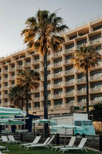 a hotel with palm trees and tables and chairs at Medplaya Hotel Pez Espada in Torremolinos