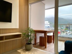 a living room with a table and a large window at Aptos perfeito para suas férias, surpreenda a todos in Ubatuba