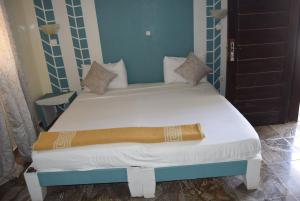 1 dormitorio con 1 cama con sábanas y almohadas blancas en Hotel Berges du Sine, en Fatick