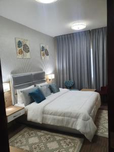 um quarto com uma grande cama branca com almofadas azuis em Marbella Holiday Homes - Al Nahda 1BHK em Dubai