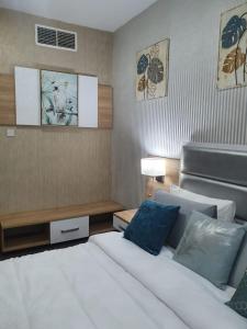 een slaapkamer met een wit bed en blauwe kussens bij Marbella Holiday Homes - Al Nahda 1BHK in Dubai