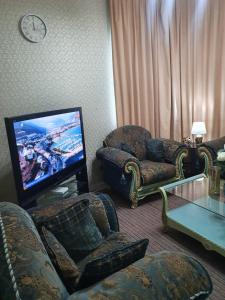 uma sala de estar com uma televisão de ecrã plano e cadeiras em Marbella Holiday Homes - Al Nahda 1BHK em Dubai