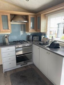 a kitchen with white cabinets and a stove top oven at Port Haverigg Millom in Millom