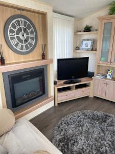 a living room with a fireplace and a clock on the wall at Port Haverigg Millom in Millom