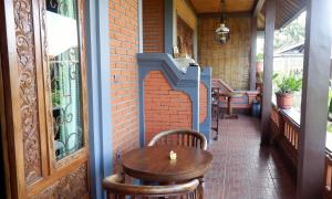 a table and chairs on a porch with a brick wall at Danasari Homestay in Ubud