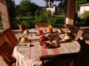 einen Tisch mit Essen auf der Terrasse in der Unterkunft La Fenière aux Hirondelles in Orange