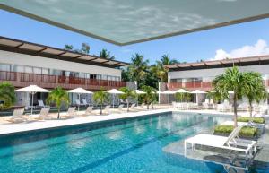 a pool at a hotel with chairs and umbrellas at Flat Completo - Ilê de Pipa in Pipa