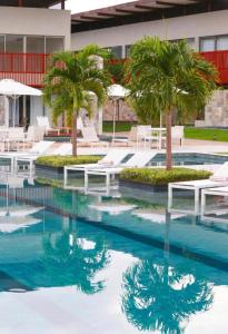 a swimming pool with palm trees and white chairs at Flat Completo - Ilê de Pipa in Pipa