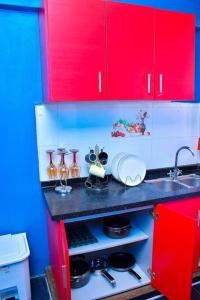 czerwona kuchnia ze zlewem i czerwonymi szafkami w obiekcie Cozier Domicile Apartments w mieście Maragoli