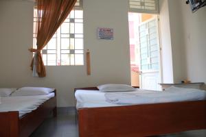 two beds in a room with two windows at Ngoc Mai Guesthouse in Buon Ma Thuot