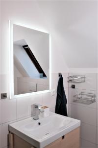 a white bathroom with a sink and a mirror at FEWO Ostseeland in Grömitz