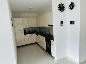 uma pequena cozinha com armários brancos e electrodomésticos pretos em Residenza Montana Lago App 8383 em Muralto