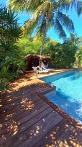 a swimming pool with a wooden deck and palm trees at Gîtes Atemoya. Petit Bas Vent Fort Royal. in Deshaies