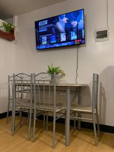 tavolo e sedie con televisore a parete di Tiffany's Staycation Unit 207 a Imus