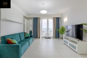 uma sala de estar com um sofá azul e uma televisão em Seafront, Studio home with Private Seaview terrace by 360 Estates em St. Paul's Bay