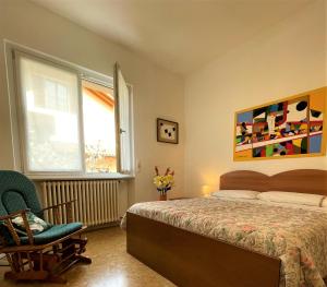 a bedroom with a bed and a chair and a window at Il nido del merlo Parcheggio e giardino in Verbania