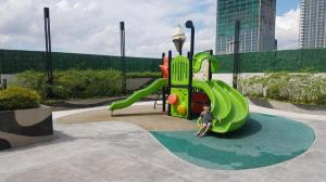 un niño está sentado en un tobogán en un patio de recreo en Apartment U Residence Tower 2 Karawaci, Tangerang Studio FULL FURNISHED SEWA, en Klapadua