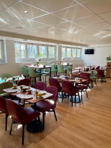 a dining room with tables and chairs and windows at Residhome Bures La Guyonnerie in Bures-sur-Yvette